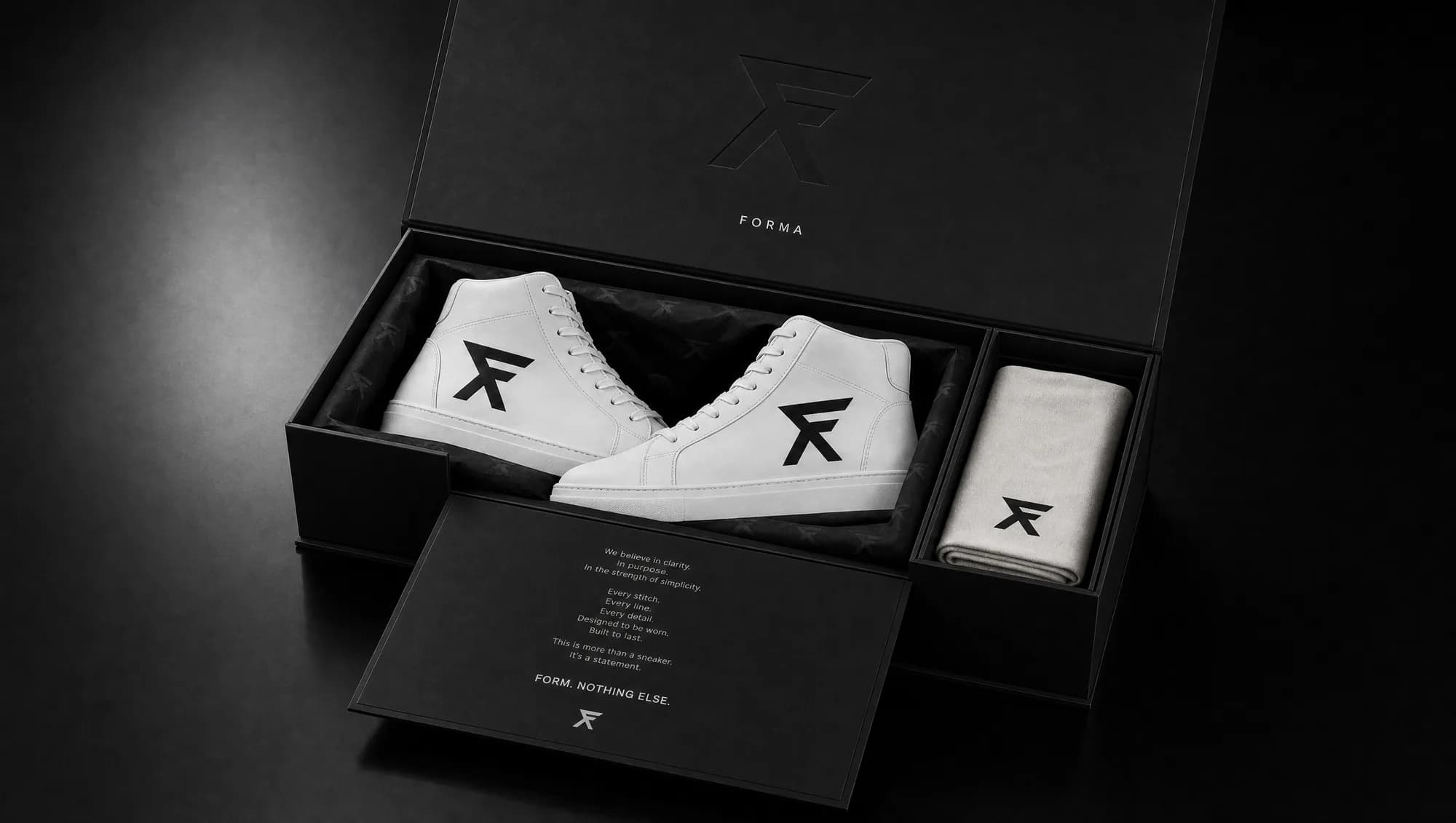 The FORMA box open, the pair seated in tonal-F tissue with the dust bag.